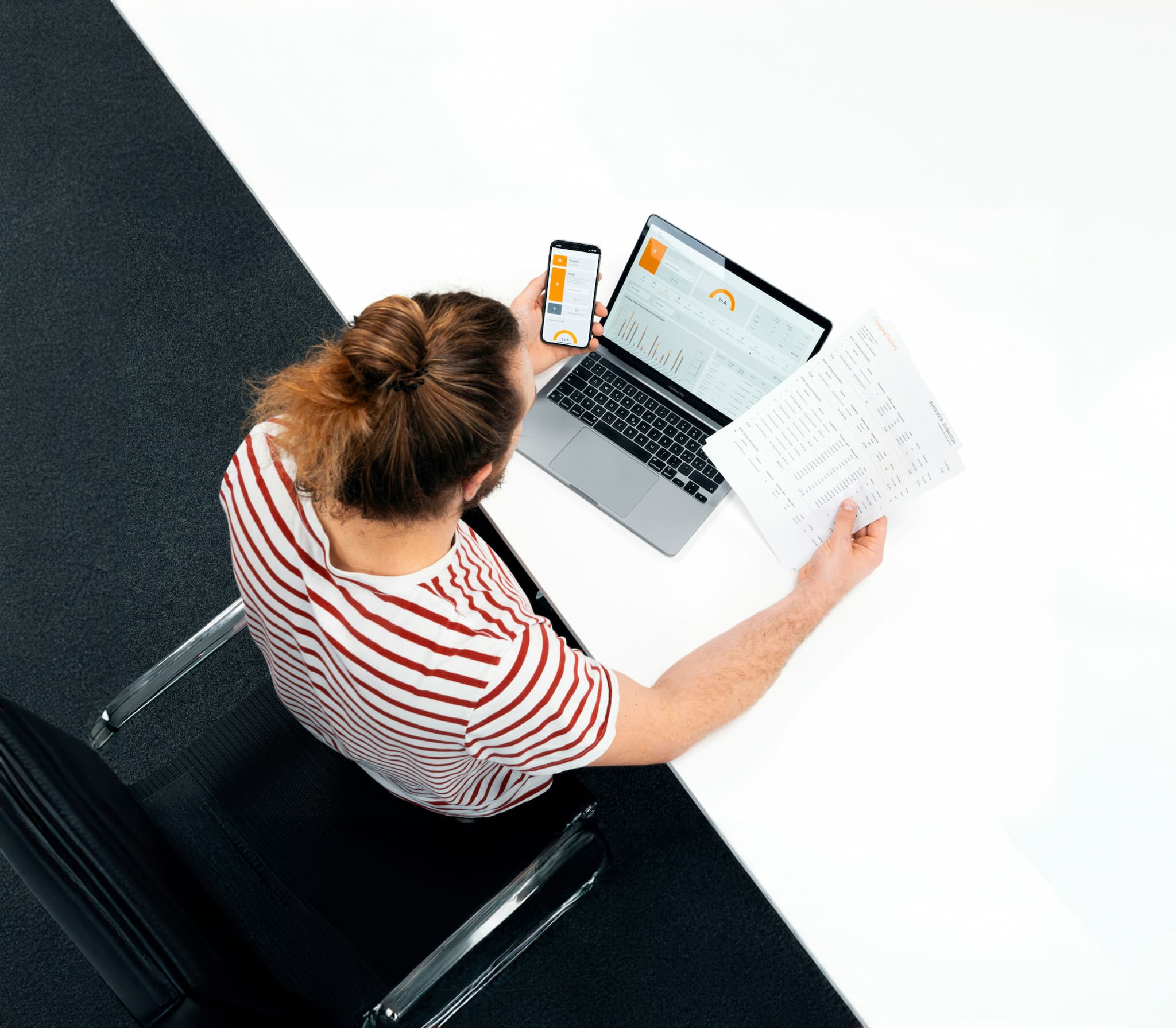 Person reviewing documents and information on a laptop and mobile phone