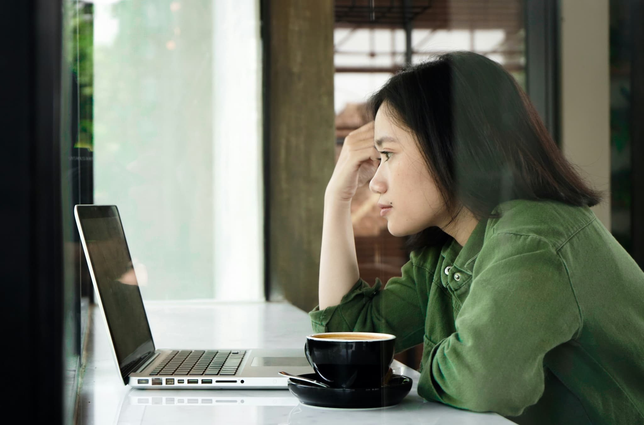 Une personne assise à côté d'un ordinateur portable, en train de lire des informations sur les brochures, les avis et les formulaires relatifs à la protection internationale